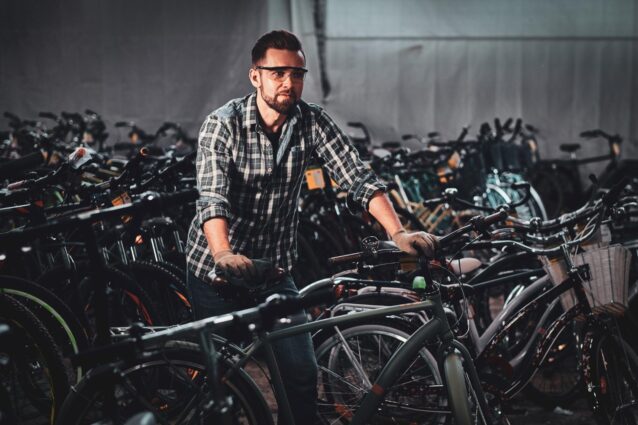 diligent hardworking man checkered shirt is working with bicycles busy warehouse