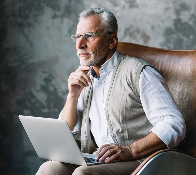 An elderly businessman using a laptop to sell his business online.