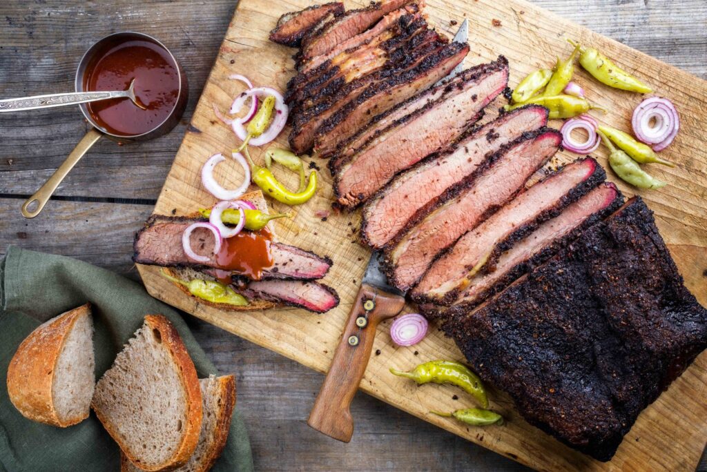 Delicious BBQ brisket on a cutting board with sliced onions and bread. Perfect for franchise brokers in the hotel industry.